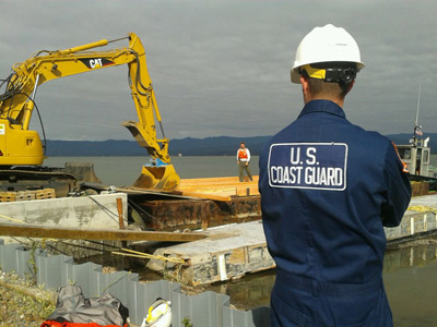 Taken by Petty Officer 3rd Class Blaine Meserve-Nibley. Chief Petty Officer Cody Staneart, a response technician with the U.S. Coast Guard's Pacific Strike Team, supervises as supplies are offloaded from the barge to Indian Island in Eureka, CA. The Coast Guard was on scene to fill the Environmental Protection Agency's request for trained personnel to conduct on-scene safety, particularly pertaining to waterside operations.